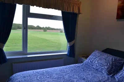 a bedroom with a bed and a large window at Little Bullocks Farm in Takeley