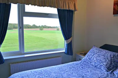 a bedroom with a bed and a large window at Little Bullocks Farm in Takeley