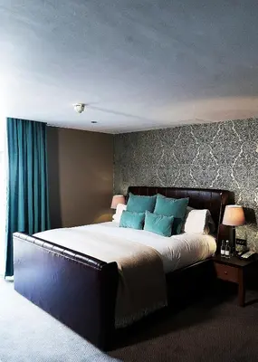 a bedroom with a large bed with blue pillows at Hotel du Vin & Bistro Cambridge in Cambridge