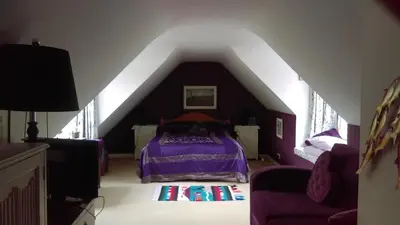 a bedroom with a purple bed in a attic at Orchard Pond Bed & Breakfast in Duxford