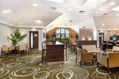 a lobby of a hotel with tables and chairs at Holiday Inn Express Colchester by IHG in Colchester