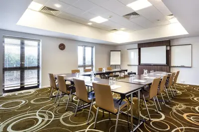 a conference room with tables and chairs and windows at Holiday Inn Express Colchester by IHG in Colchester