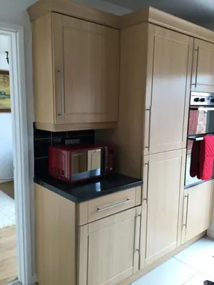 a small kitchen with a microwave and a refrigerator at 4 Bed House next to Basildon Town Centre in Basildon