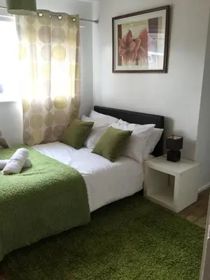 a bedroom with a large white bed with green pillows at 4 Bed House next to Basildon Town Centre in Basildon