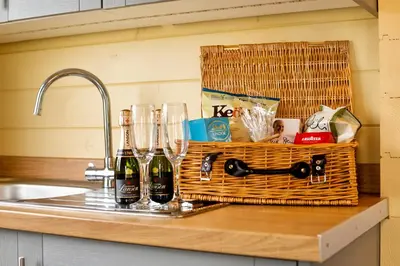 a basket of wine bottles and glasses on a kitchen counter at The Retreat Log Cabin in Sudbury
