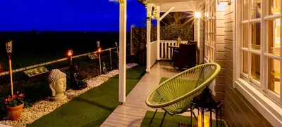 a porch of a house at night with a chair at The Retreat Log Cabin in Sudbury