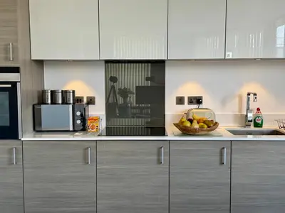 a kitchen with white cabinets and a bowl of fruit at Signet Apartments - Ceres in Cambridge