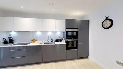 a kitchen with stainless steel appliances and a clock on the wall at Signet Apartments - Vesta in Cambridge