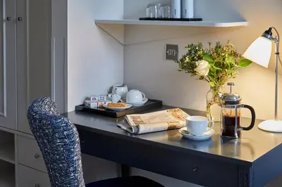 a desk with a chair and a vase of flowers at Hertford House in Hertford