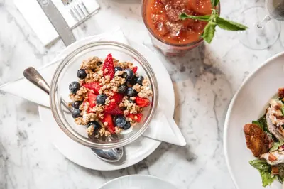 a table topped with a bowl of granola and berries at Hertford House in Hertford
