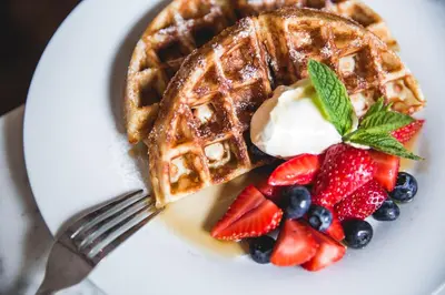 a plate with a waffle with fruit and whipped cream at Hertford House in Hertford