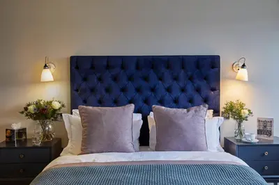 a bedroom with a large blue bed with pillows at Hertford House in Hertford