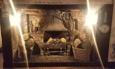 a brick fireplace with a stove with logs in it at The White Horse Inn in Cambridge