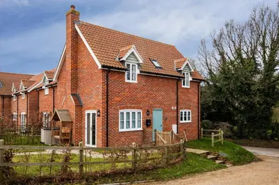 a red brick house with a fence in front of it at 1 Roseanna Cottage, Middleton - Aldeburgh Coastal Cottages in Middleton