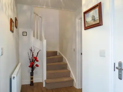 a staircase in a home with a vase of flowers at 1 Roseanna Cottage, Middleton - Aldeburgh Coastal Cottages in Middleton