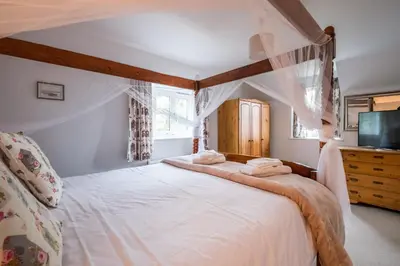 a bedroom with a canopy bed with white sheets at 1 Roseanna Cottage, Middleton - Aldeburgh Coastal Cottages in Middleton
