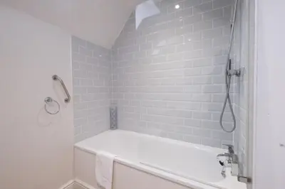 a white bathroom with a tub and a shower at 1 Roseanna Cottage, Middleton - Aldeburgh Coastal Cottages in Middleton