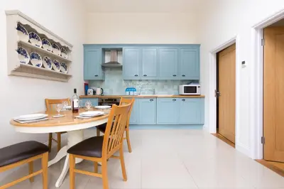 a kitchen with blue cabinets and a table and chairs at 2 Suffolk Cottage, Knodishall - Aldeburgh Coastal Cottages in Aldringham