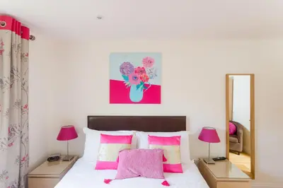 a bedroom with a bed with pink pillows and a mirror at 2 Suffolk Cottage, Knodishall - Aldeburgh Coastal Cottages in Aldringham