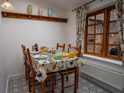 a dining room with a table and chairs and a window at All Seasons Cottage Breaks in Saxmundham