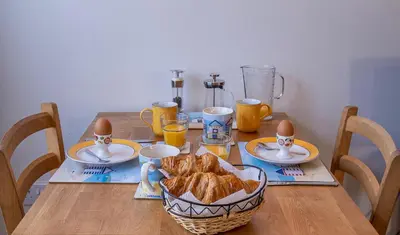 a table with a basket of bread and eggs on it at All Seasons Cottage Breaks in Saxmundham