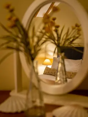 a mirror reflecting a bedroom with a bed and a lamp at All Seasons Cottage Breaks in Saxmundham