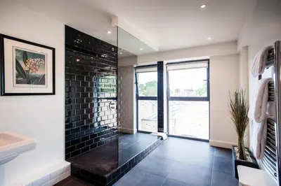 a bathroom with a walk in shower next to a window at The Varsity Hotel & Spa in Cambridge
