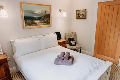 a bedroom with a bed with a towel on it at Creeksea Place Barns in Burnham on Crouch