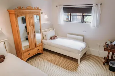 a small bedroom with two beds and a mirror at Creeksea Place Barns in Burnham on Crouch