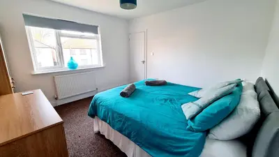 a bedroom with a blue bed and a couch at Airport Reach in Southend-on-Sea