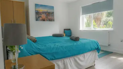 a bedroom with a bed with blue sheets and a window at Airport Reach in Southend-on-Sea