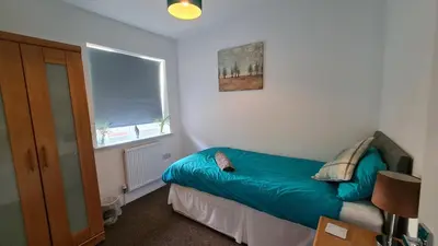 a small bedroom with a blue bed and a window at Airport Reach in Southend-on-Sea