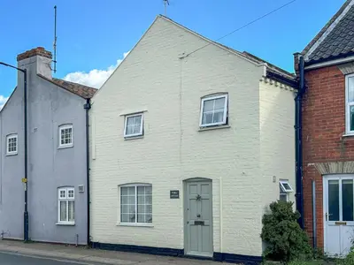 a white house with a white door on a street at Pebble Cottage in Aldeburgh