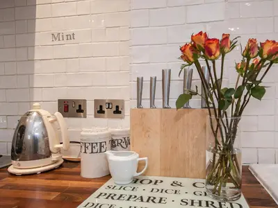 a vase of flowers sitting on a counter with a coffee maker at Pebble Cottage in Aldeburgh