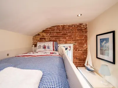 a bed in a room with a brick wall at Pebble Cottage in Aldeburgh