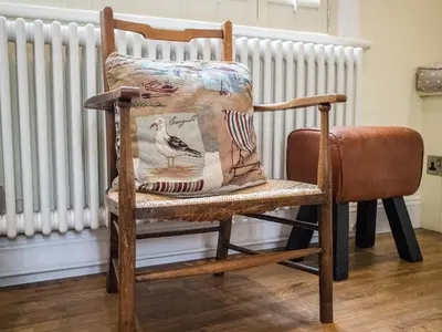 a wooden rocking chair with a pillow on it at Pebble Cottage in Aldeburgh