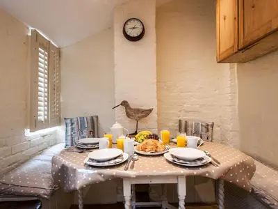 a table with a plate of food and a clock at Pebble Cottage in Aldeburgh