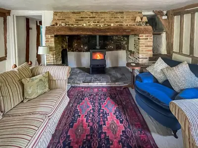 a living room with a couch and a fireplace at Thatched Cottage in Saxmundham