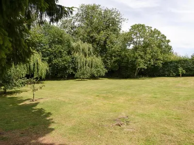 a large grass field with trees in the background at Thatched Cottage in Saxmundham