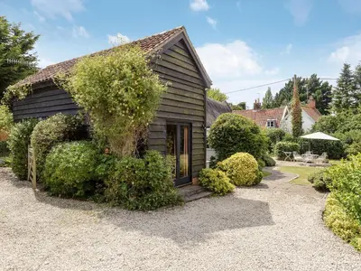 a small house with bushes around it at Thatched Cottage in Saxmundham