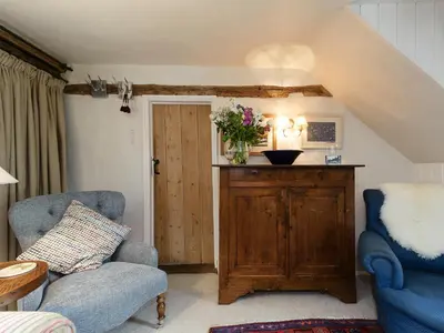 a living room with two chairs and a wooden cabinet at Thatched Cottage in Saxmundham