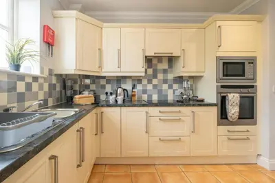 a kitchen with white cabinets and a sink at 1 Hazelwood, Aldeburgh in Aldringham