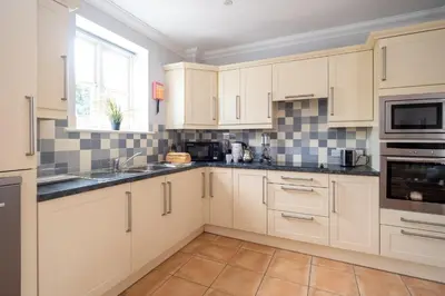 a kitchen with white cabinets and a window at 1 Hazelwood, Aldeburgh in Aldringham