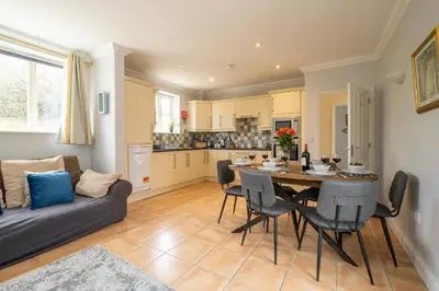 a kitchen and living room with a table and a couch at 1 Hazelwood, Aldeburgh in Aldringham