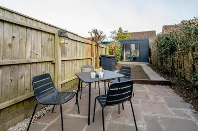 a table and chairs on a patio with a fence at Sleepers Cottage in Aldeburgh