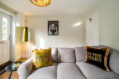a living room with a gray couch with two pillows at Sleepers Cottage in Aldeburgh