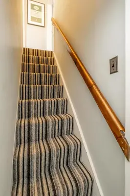 a staircase with a striped carpet and a stair case at Sleepers Cottage in Aldeburgh