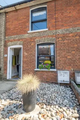 a brick building with a window and a potted plant at Sleepers Cottage in Aldeburgh