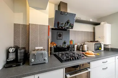 a kitchen with a stove top oven next to a microwave at Sleepers Cottage in Aldeburgh