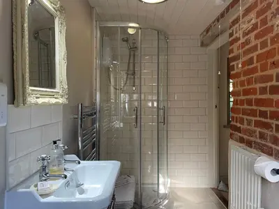 a bathroom with a sink and a glass shower at Dairy Cottage Luxury B&B in Attleborough
